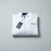 Folded white jacket with Tommy Hilfiger logo on a gray background
